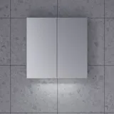 Stylish and minimalist bathroom inspiration featuring a micro basin with a small vanity unit, a square mirror with rounded corners and a lamp, and an elegant mirror cabinet.