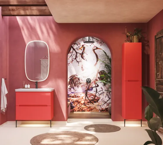 Bathroom inspiration with red walls, softly shaped red vanity and tall cabinet, elegant white sink and beautiful oval mirror with light, creating a vintage look together with the natural surroundings
