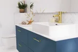 Bathroom inspiration with bathroom furniture in modern blue colour, elegant countertop basin and large square mirror with light, white herringbone tiles create a stylish and classic look