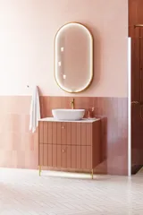 Large vintage retro bathroom inspiration with a terracotta-colored grooved vanity, elegant thin countertop with a beautiful vessel sink, stylish oval mirror with brass edge. Pink tiles and grey herringbone tiles give a romantic and feminine look