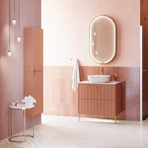 Large vintage retro bathroom inspiration with a terracotta-colored grooved vanity, elegant thin countertop with a beautiful vessel sink, stylish oval mirror with brass edge. Pink tiles and grey herringbone tiles give a romantic and feminine look