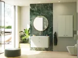 Stylish and luxurious bathroom with gentle green tones, a large elegant round mirror, and a modern, sophisticated green toilet