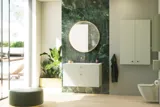 Stylish and luxurious bathroom with gentle green tones, a large elegant round mirror, and a modern, sophisticated green toilet