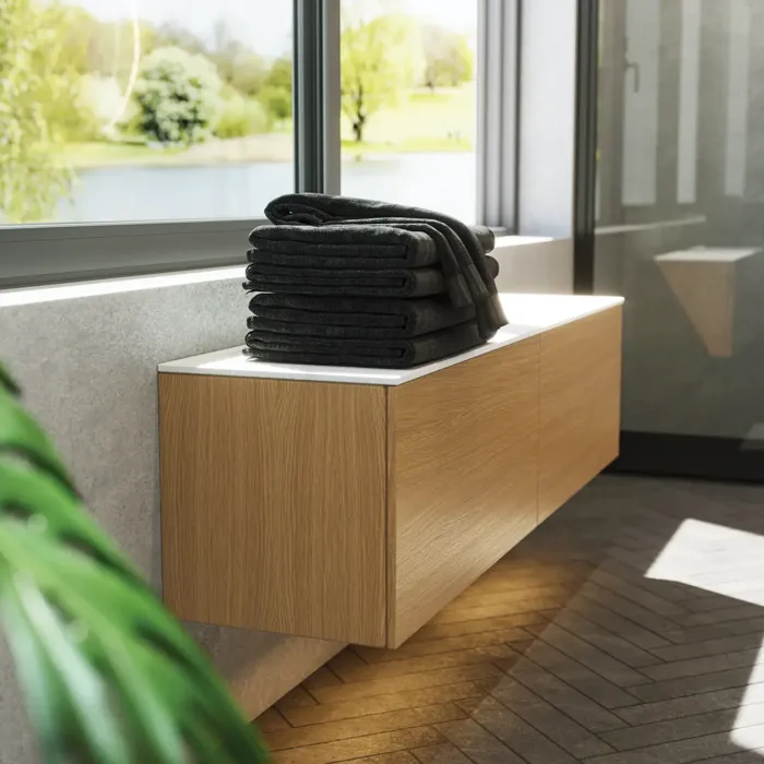 Minimalist and sleek bathroom inspiration with vanity unit, base cabinets, and tall cabinets in golden oak, large round mirror with light control, colored toilet, and countertop sink