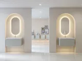 Stylish and modern bathroom inspiration with oval mirrors with light control, stone sinks, and vanity units with fine and elegant grooves in a minimalist design, the bathroom has a light and airy atmosphere with elegant lighting and refined details