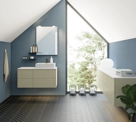 Bathroom with slanted ceiling inspiration, beige furniture with grooves, elegant countertop and square sink, beautiful mirror with shelves, blue walls, large windows, and black herringbone floor give a bright, urban look.