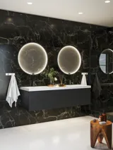 Elegant and modern bathroom inspiration with dark marble walls, round illuminated mirrors with black frames, wall-mounted vanity unit with double sinks, and a spacious shower area
