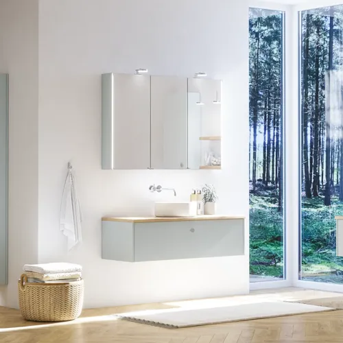 Large bathroom inspiration in Nordic style with bathroom furniture in light blue colour and wooden countertop with elegant countertop basin, herringbone wooden floor creating a bright and classic style