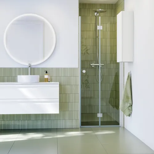 Bathroom inspiration with white bathroom furniture, elegant round mirror and shower niche with folding door in clear glass and profiles in satin, green oblong tiles give a sophisticated look.
