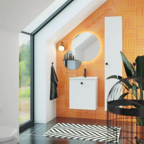 Bathroom with sloping ceiling inspiration with small white vanity unit and tall cabinet with round black handles, as well as beautiful round mirror, orange tiles give a fresh and modern look.