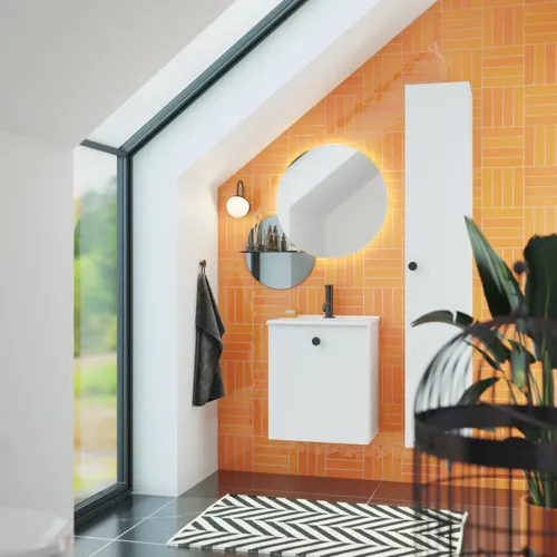 Bathroom with sloping ceiling inspiration with small white vanity unit and tall cabinet with round black handles, as well as beautiful round mirror, orange tiles give a fresh and modern look.