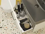 Small bathroom inspiration with a white vanity with black handle and black elegant sink, beautiful round mirror with black edge, offset wall cabinets, and terrazzo wall and floor, as well as yellow walls, provide a bold and modern look.