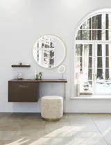 Nordic style bathroom inspiration with vanity unit and base cabinets in smoked oak, makeup area, side-mounted sink, round mirror with brass frame, and visible charming wooden beams.