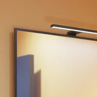 Small bathroom inspiration with slanted, warm yellow walls, and a minimalist square mirror with a sleek black edge, along with an elegant mirror lamp that adds a touch of elegance to your bathroom.