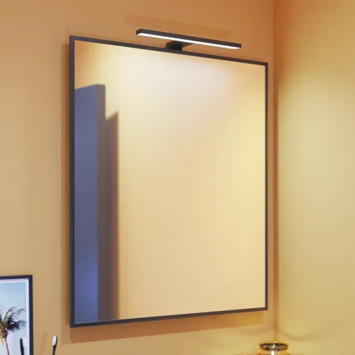 Small bathroom inspiration with slanted, warm yellow walls, and a minimalist square mirror with a sleek black edge, along with an elegant mirror lamp that adds a touch of elegance to your bathroom.