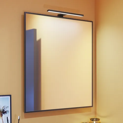Small bathroom inspiration with slanted, warm yellow walls, and a minimalist square mirror with a sleek black edge, along with an elegant mirror lamp that adds a touch of elegance to your bathroom.