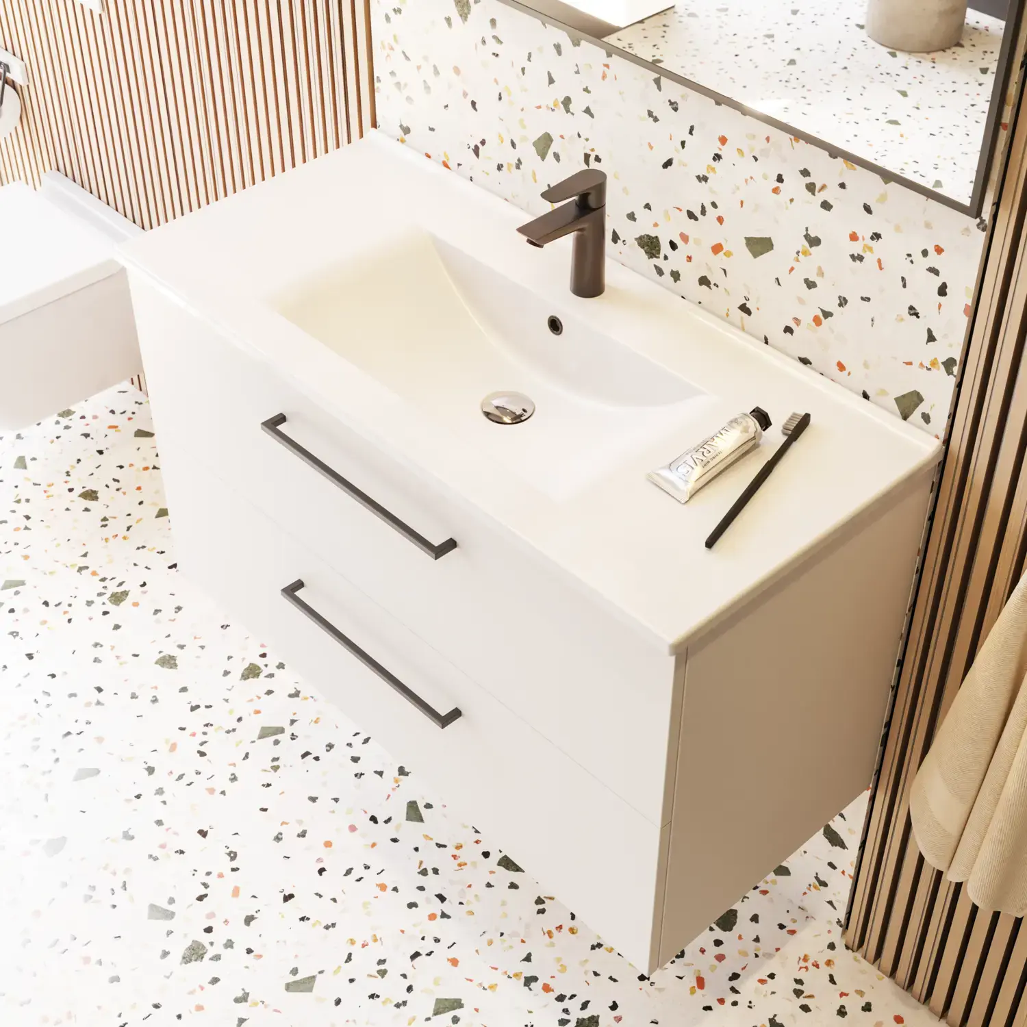Large bathroom inspiration with bathroom furniture in matt white with elegant washbasin and square mirror with black rim and lamp, terrazzo wall and floor and plants on the wall for a modern and sophisticated look.