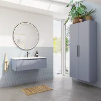 Bathroom inspiration with elongated light blue tiles and concrete floor, elegant light blue vanity unit with beautiful narrow stripes, sleek and thin sink, double tall cabinet with narrow stripes, and a minimalist round mirror with a black edge and light.