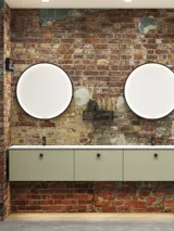 Raw and modern bathroom in an urban style. Beautiful vanity units and black framed round mirrors