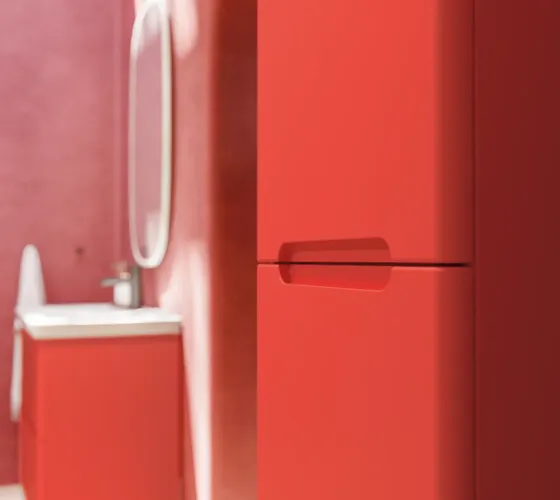 Bathroom inspiration with red walls, softly shaped red vanity and tall cabinet, elegant white sink and beautiful oval mirror with light, creating a vintage look together with the natural surroundings